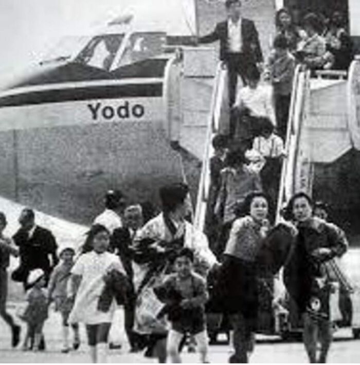 Black and white photo of people disembarking Yodo airplane, a weird history moment capturing past travel scenes.