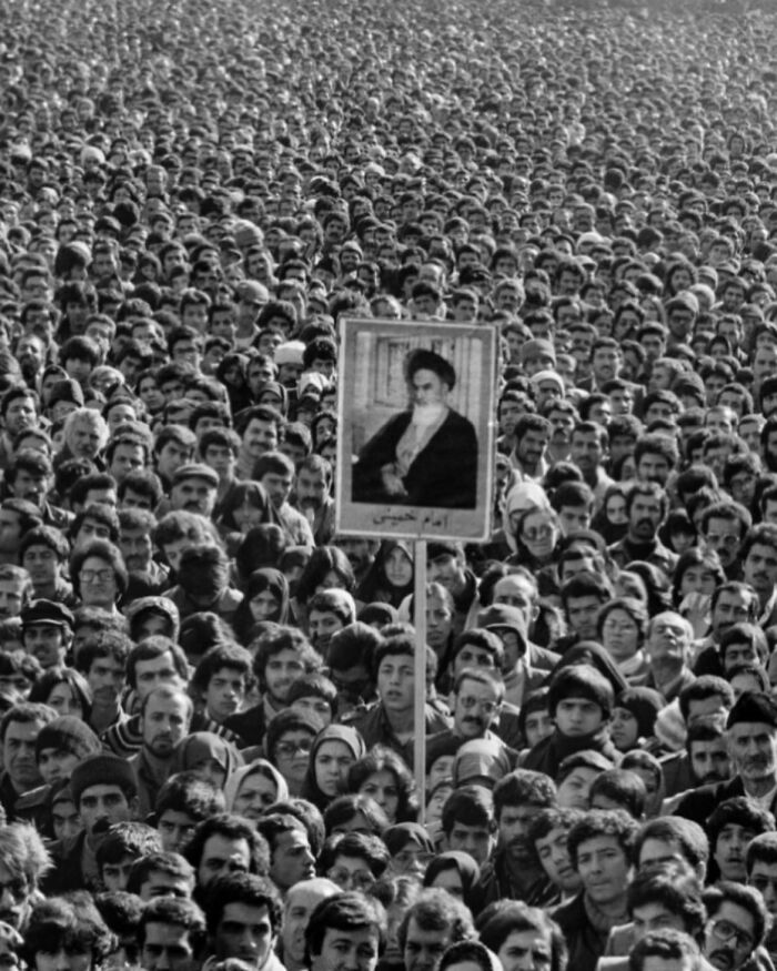 Massive crowd holding a portrait in a historical black and white photo highlighting weird history moments.
