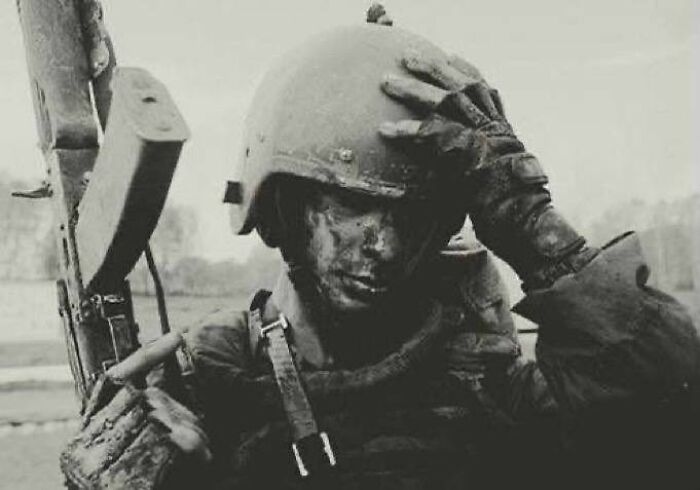 Soldier covered in mud holding a rifle, wearing a helmet and gloves in a weird history pic showing a tense moment.