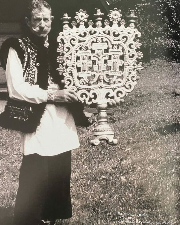 Black and white photo of a man in traditional clothing holding an ornate religious artifact, a weird history pic.