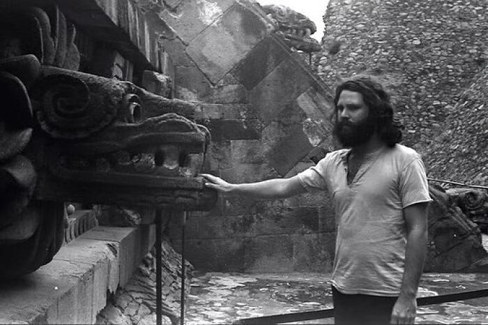Man with a beard touching an ancient stone carving in a historical site, showcasing weird history pics from the past.
