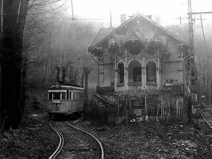 Old tram passing a vintage house in a misty forest setting, showcasing weird history pics from the past.