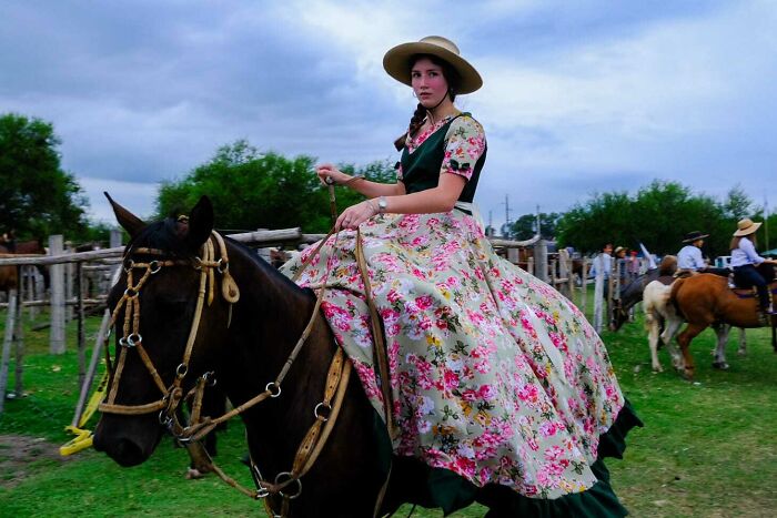 Young woman in traditional floral dress riding a horse during a street photo capturing everyday life by Stéphane Kyndt.