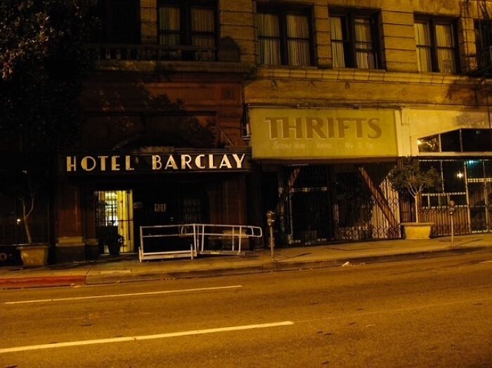 Nighttime street photo showing Hotel Barclay entrance and a closed thrift store, capturing everyday life in an urban setting.
