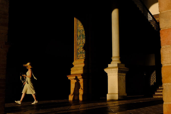 Person walking past sunlit columns in a street photo capturing everyday life by Stéphane Kyndt.