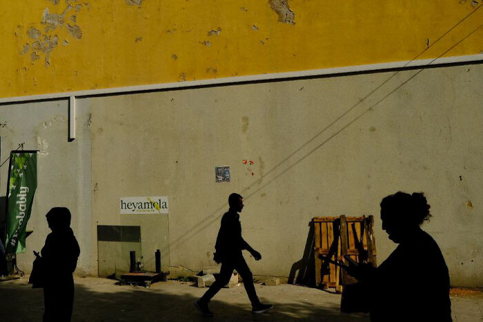 Silhouettes of people walking and standing against a textured wall capturing everyday life in street photos by Stéphane Kyndt