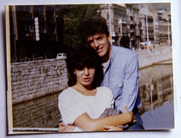 Young couple embracing near a historic canal, capturing a candid and iconic moment in history.