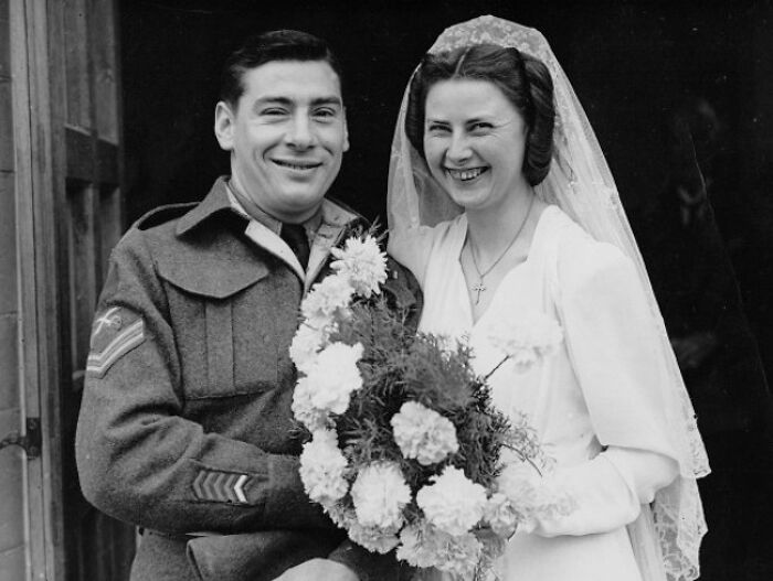 Smiling bride and groom in 1940s wedding attire, capturing love in the shadow of war with vintage wedding photos.