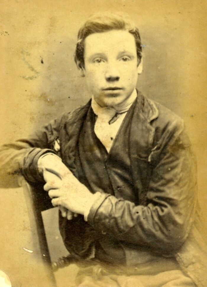 Vintage historical mugshot of a young man in worn clothing, showcasing intriguing stories behind historical mugshots.