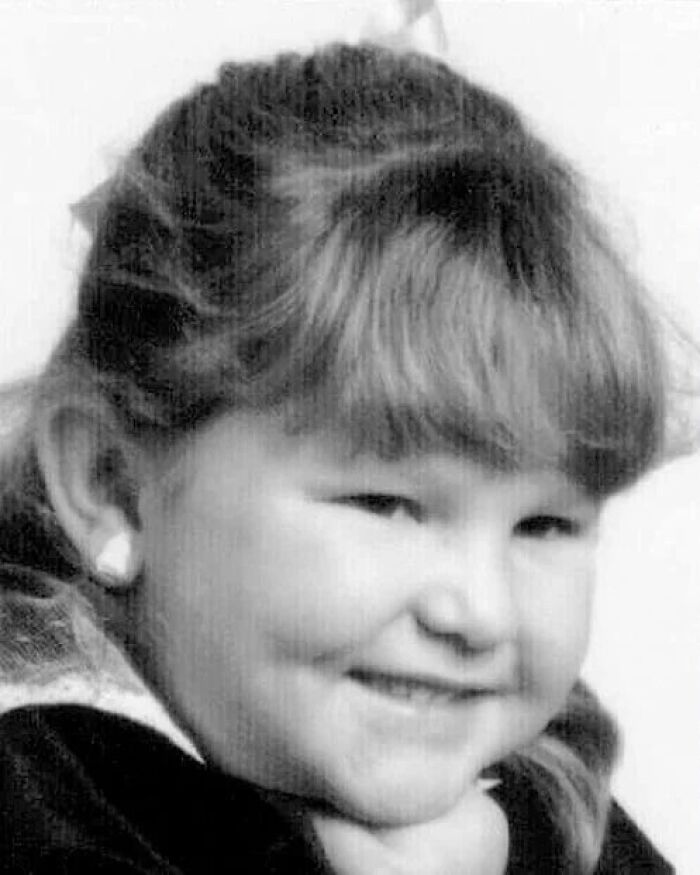 Black and white photo of a young girl smiling, part of chilling disappearances from the 90s that remain baffling.