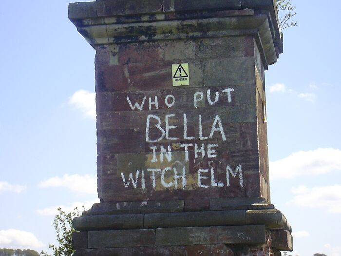 Graffiti on stone monument referencing baffling unsolved mysteries of Bella in the Witch Elm under daylight sky.