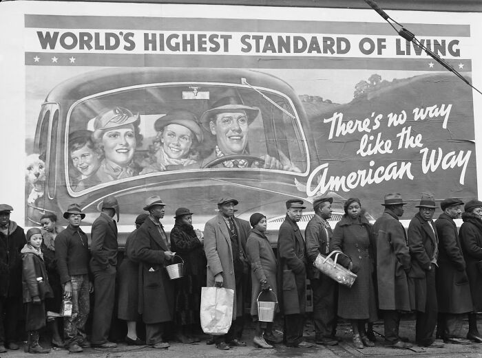 Historic black and white photo showing a line of people in front of an American Way mural, capturing iconic moments in history.