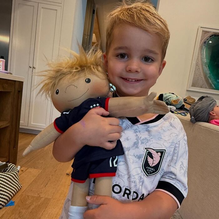 Young boy smiling and holding a custom doll representing rare health conditions and individual needs.