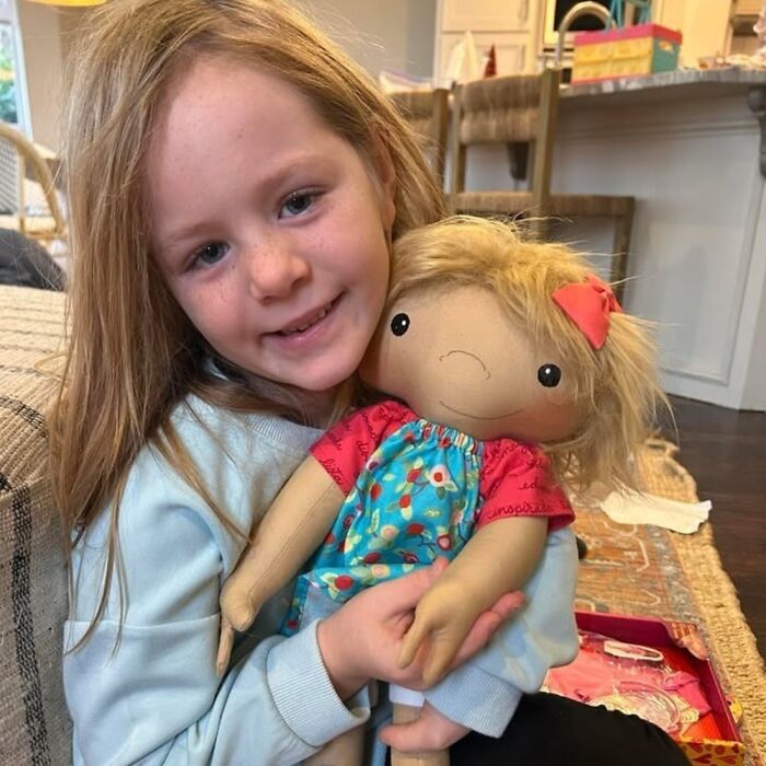 Young girl smiling and holding a custom doll representing rare health conditions and individual child needs.