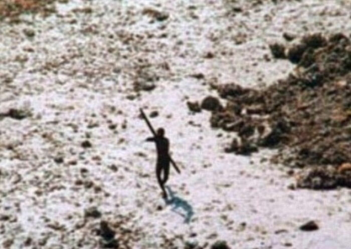 Silhouetted Indigenous tribe member walking with a spear on rocky terrain linked to influencer TikTok stunt controversy.