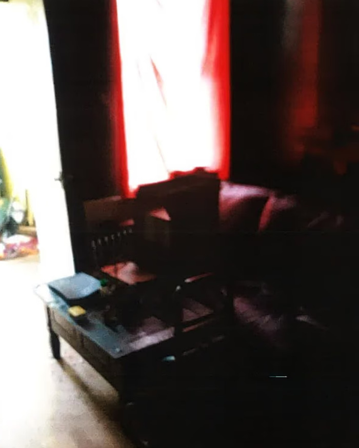 Dimly lit living room with a red curtain, wooden table, and couch, related to toddler vegan diet signs ignored.