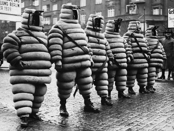 Men wearing bizarre vintage gas protective suits standing in a row, illustrating unfamiliar parts of history.