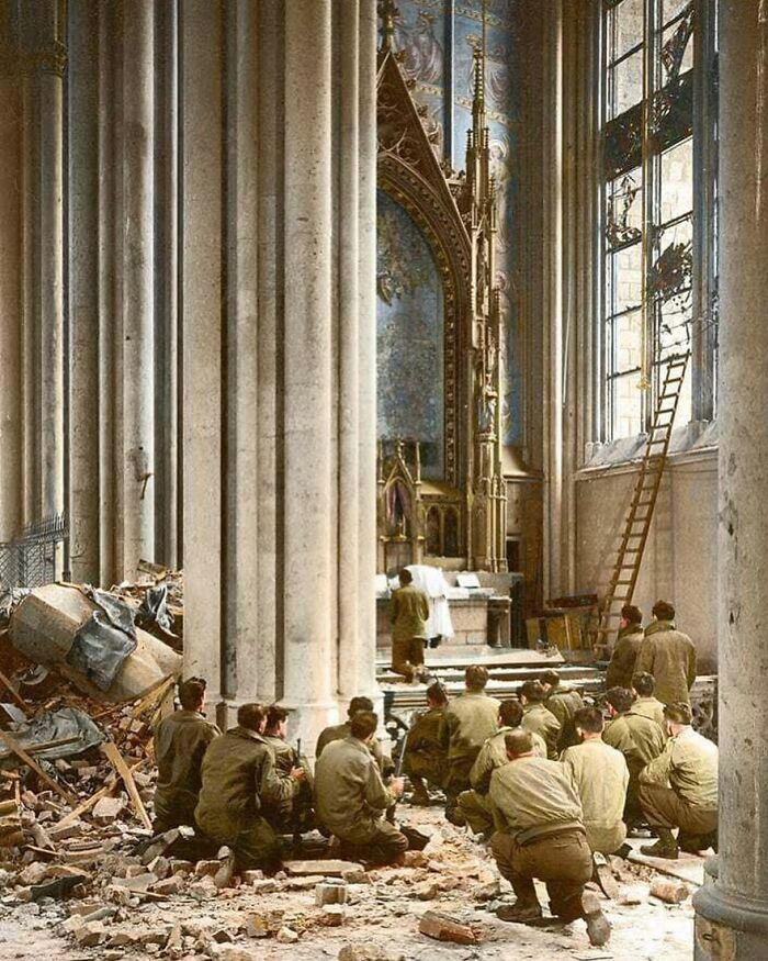 Soldiers praying inside a damaged historic church, revealing unfamiliar parts of history during wartime restoration efforts.