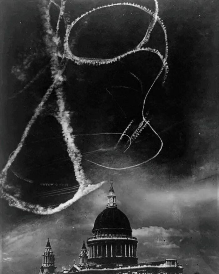 Black and white historic photo showing unusual WWII airplane smoke trails above iconic St. Paul's Cathedral in history.