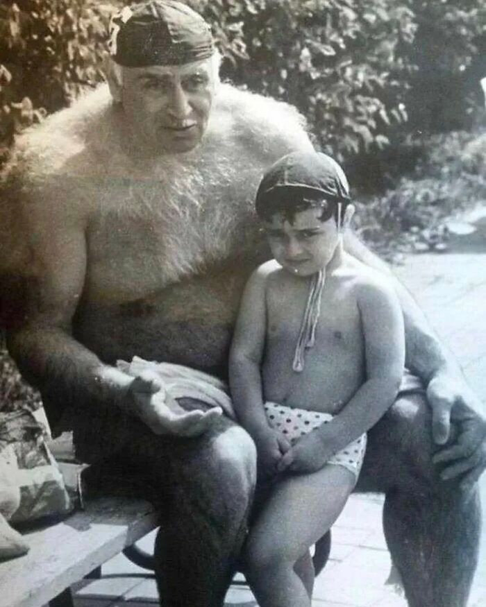 Vintage black and white photo showing a man with extra body hair sitting with a child, highlighting unfamiliar parts of history.
