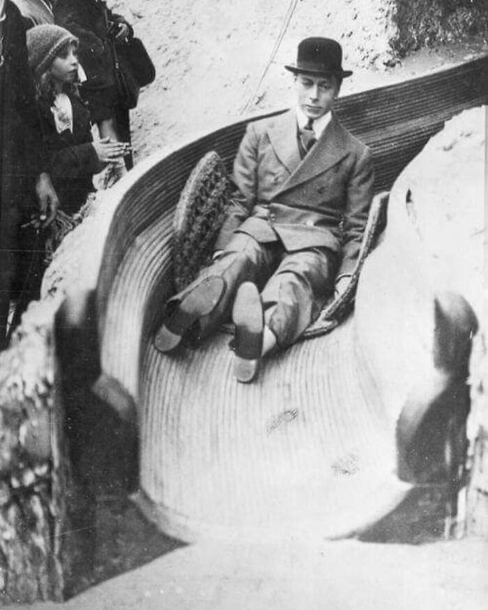 Man in vintage suit and hat sliding down an early amusement ride, showcasing unfamiliar parts of history in black and white.