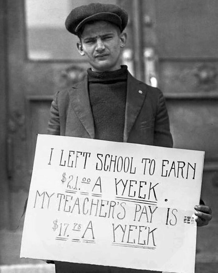 Young boy holding a sign about wages, revealing unfamiliar parts of history and childhood labor conditions.