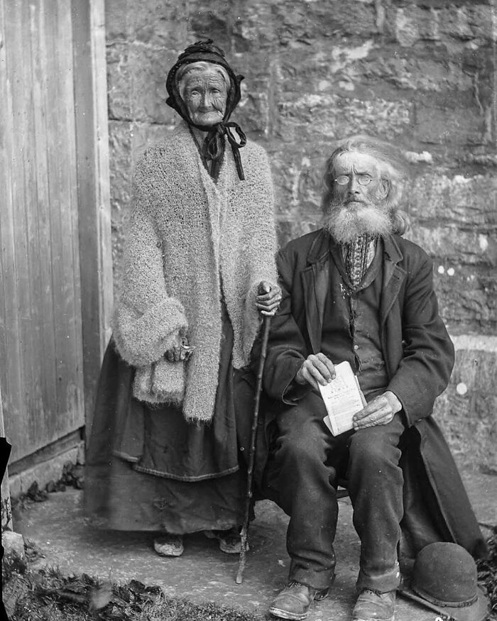 Elderly couple in historical clothing holding a paper, representing unfamiliar parts of history from old photos and facts.