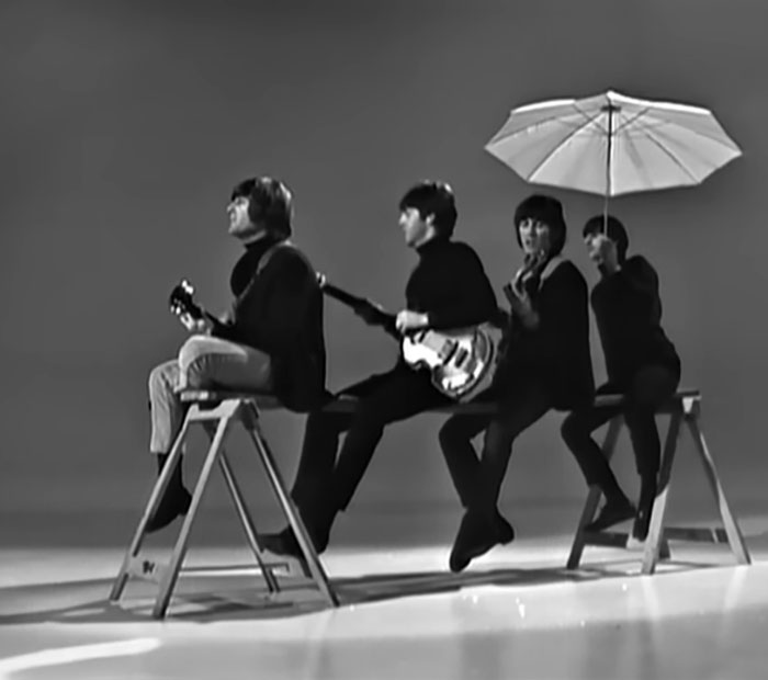 Black and white photo of four musicians with guitars and an umbrella, capturing new facts moments in music history.