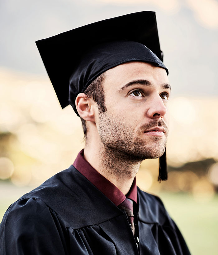 Young man in graduation cap and gown looking inspired, symbolizing new facts and knowledge gained.