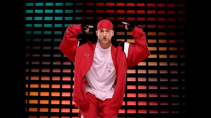 Man in red outfit pointing to himself against a colorful tiled background, illustrating new facts shared with others.