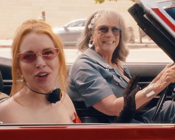 Jamie Lee Curtis smiling with fuller lips, wearing sunglasses and driving a red convertible with a female companion. Jamie Lee Curtis smiling with fuller lips, wearing sunglasses and driving a red convertible with a female companion.