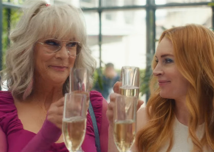 Jamie Lee Curtis with fuller lips raising a toast with a friend, both smiling and holding champagne glasses outdoors. Jamie Lee Curtis with fuller lips raising a toast with a friend, both smiling and holding champagne glasses outdoors.