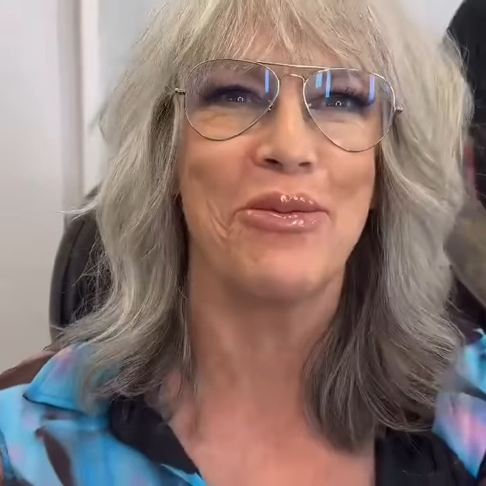 Jamie Lee Curtis with gray hair and glasses showing dramatically fuller lips in a stylish, casual setting. Jamie Lee Curtis with gray hair and glasses showing dramatically fuller lips in a stylish, casual setting.