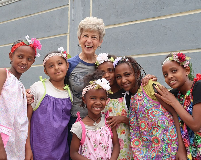 Group of smiling children with flowers in their hair and an older woman, reflecting Brad Pitt's final public message to his mom. Group of smiling children with flowers in their hair and an older woman, reflecting Brad Pitt's final public message to his mom.