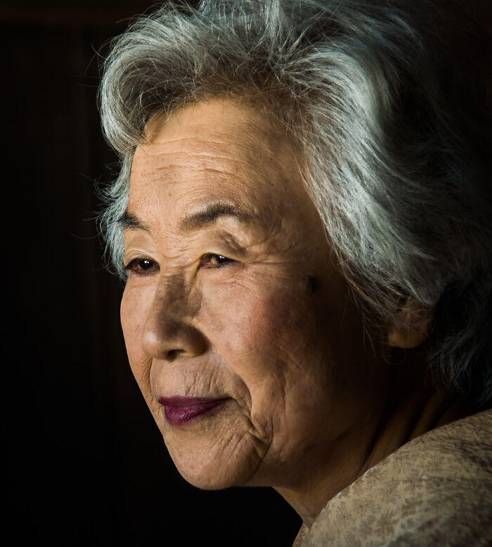 Portrait of an elderly woman with gray hair, showcasing cultural beauty captured by a photographer traveling worldwide.