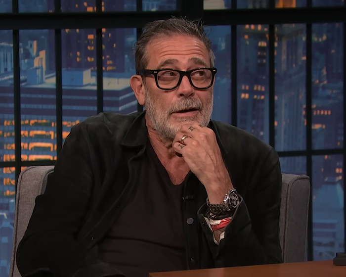 Jeffrey Dean Morgan wearing glasses and black jacket, responding to viral theory during a talk show interview.