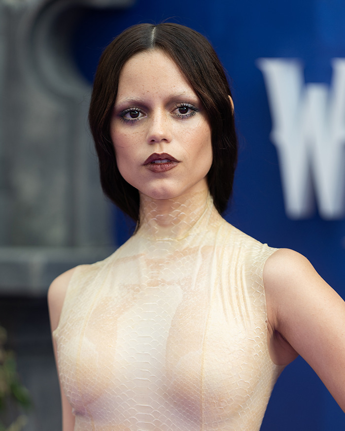 Young woman with sleek dark hair and neutral makeup showcasing the new tired girl beauty trend popular among Gen Z women.