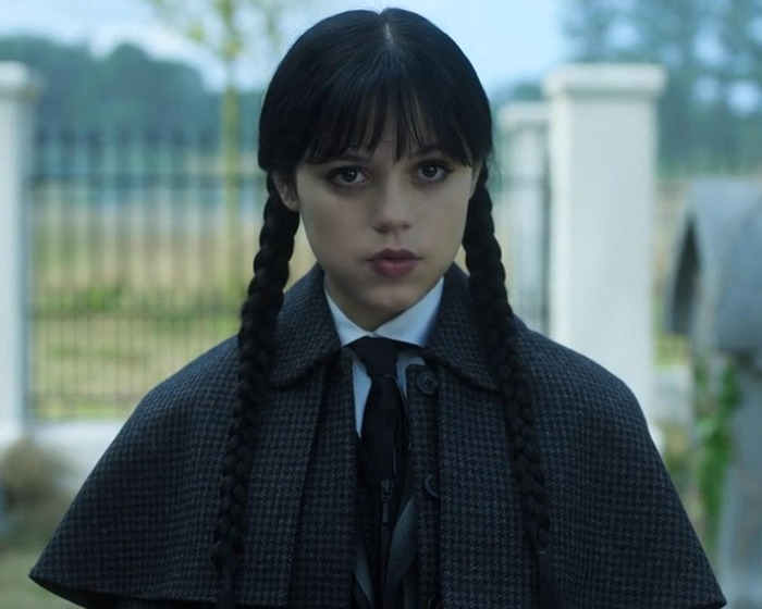 Young woman with braided pigtails and dark makeup showcasing the tired girl beauty trend popular with Gen Z women.