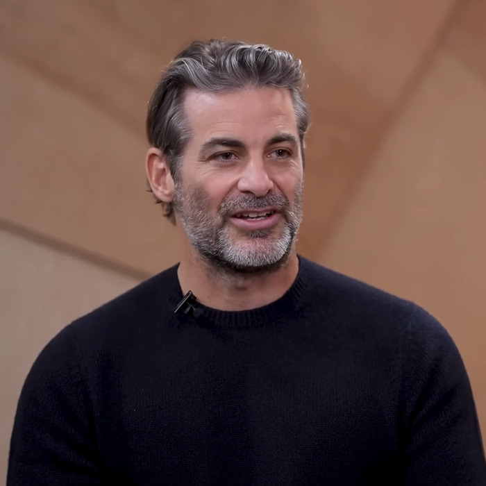 Man with salt and pepper hair and beard wearing a black sweater in an indoor setting discussing Jennifer Aniston purse reveal. Man with salt and pepper hair and beard wearing a black sweater in an indoor setting discussing Jennifer Aniston purse reveal.