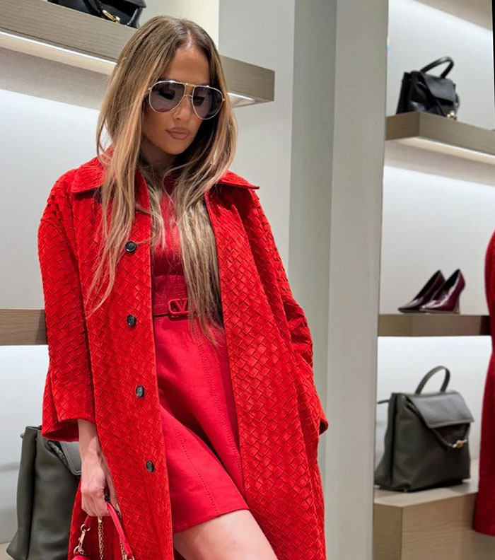 Jennifer Lopez wearing bold red outfit and sunglasses inside a luxury store after Chanel store entry refusal.