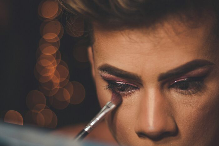 Person applying makeup, highlighting issues related to gender-based double standards in personal appearance.