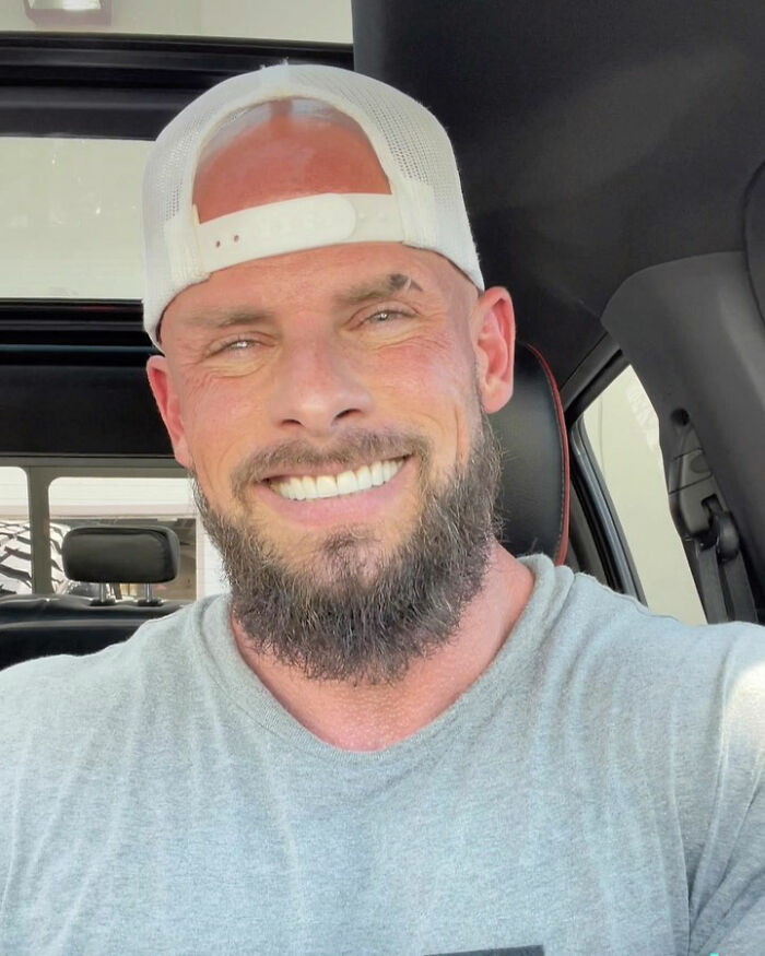 Joey Swoll smiling in a gray shirt and white cap, known for his applauded response to height-related comments about men.
