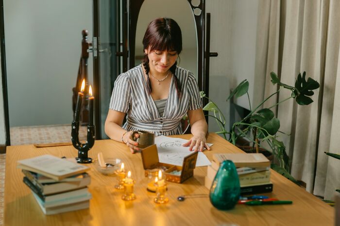 Woman practicing psychic reading with candles, drawings, and books, illustrating people experiencing psychic predictions.