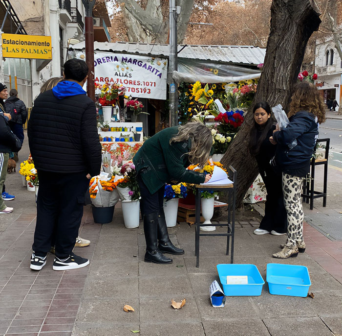 People gather outdoors at a flower shop, signing a petition in support of Free Juan, the celebrity duck controversy.