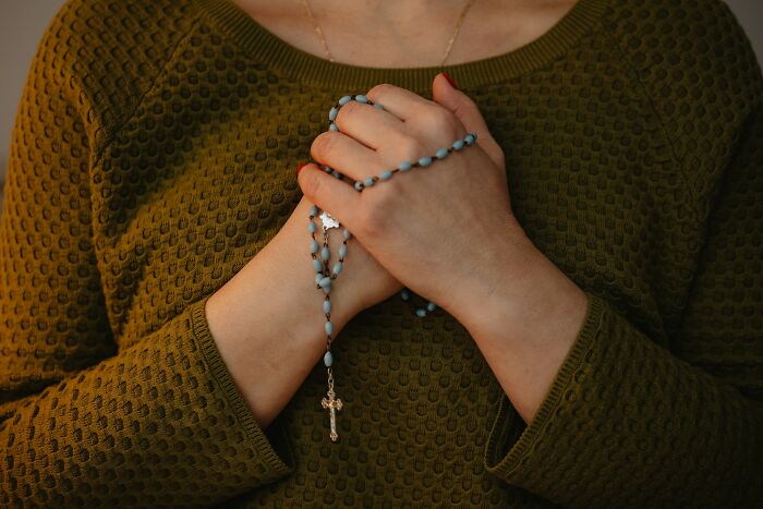Hands clasped holding rosary beads, symbolizing reflection and caution about job interview red flags.