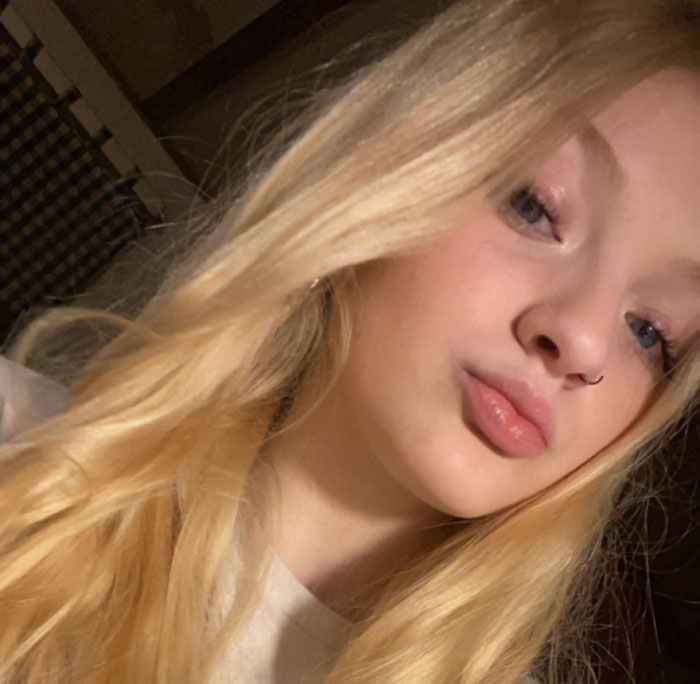 Teen with long blonde hair and nose ring posing for a close-up selfie, related to road rage incident and pregnancy loss. Teen with long blonde hair and nose ring posing for a close-up selfie, related to road rage incident and pregnancy loss.