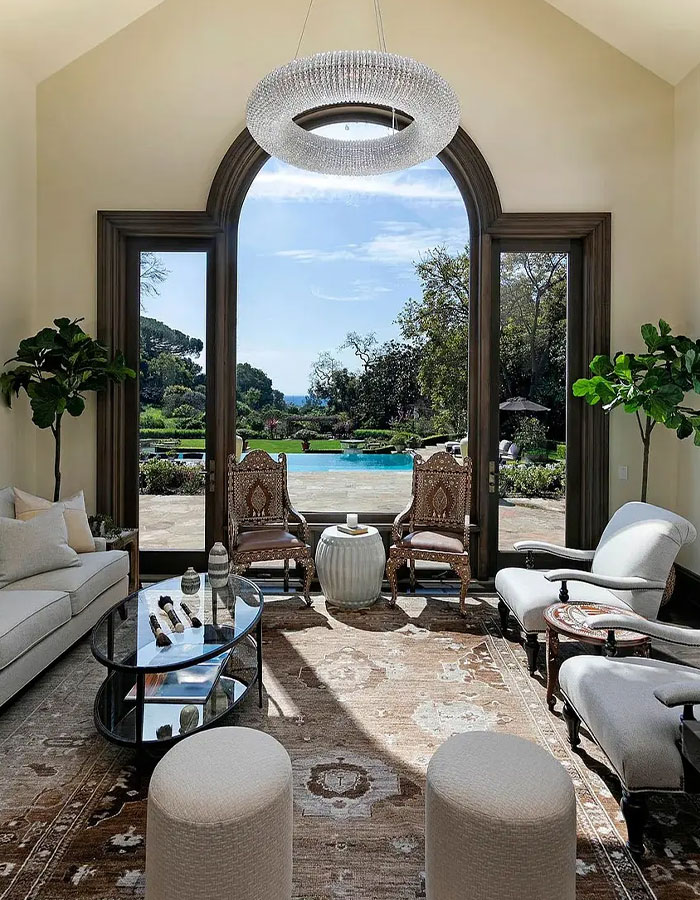 Luxury living room with large arched windows overlooking a pool, representing Katy Perry $15 million property rental. - 5