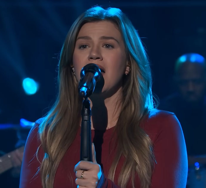 Kelly Clarkson singing on stage with long hair, expressing emotion after messy painful divorce and ex’s passing. Kelly Clarkson singing on stage with long hair, expressing emotion after messy painful divorce and ex’s passing.