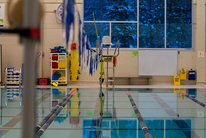 Indoor swimming pool lanes with a lifeguard chair and equipment, reflecting a calm and quiet atmosphere.