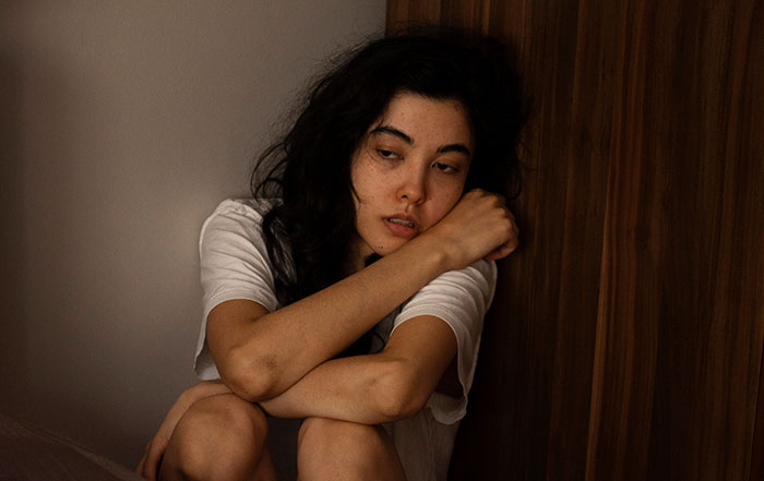 Young woman sitting alone looking distressed, depicting a survivor of kidnapping sharing horrifying experiences.